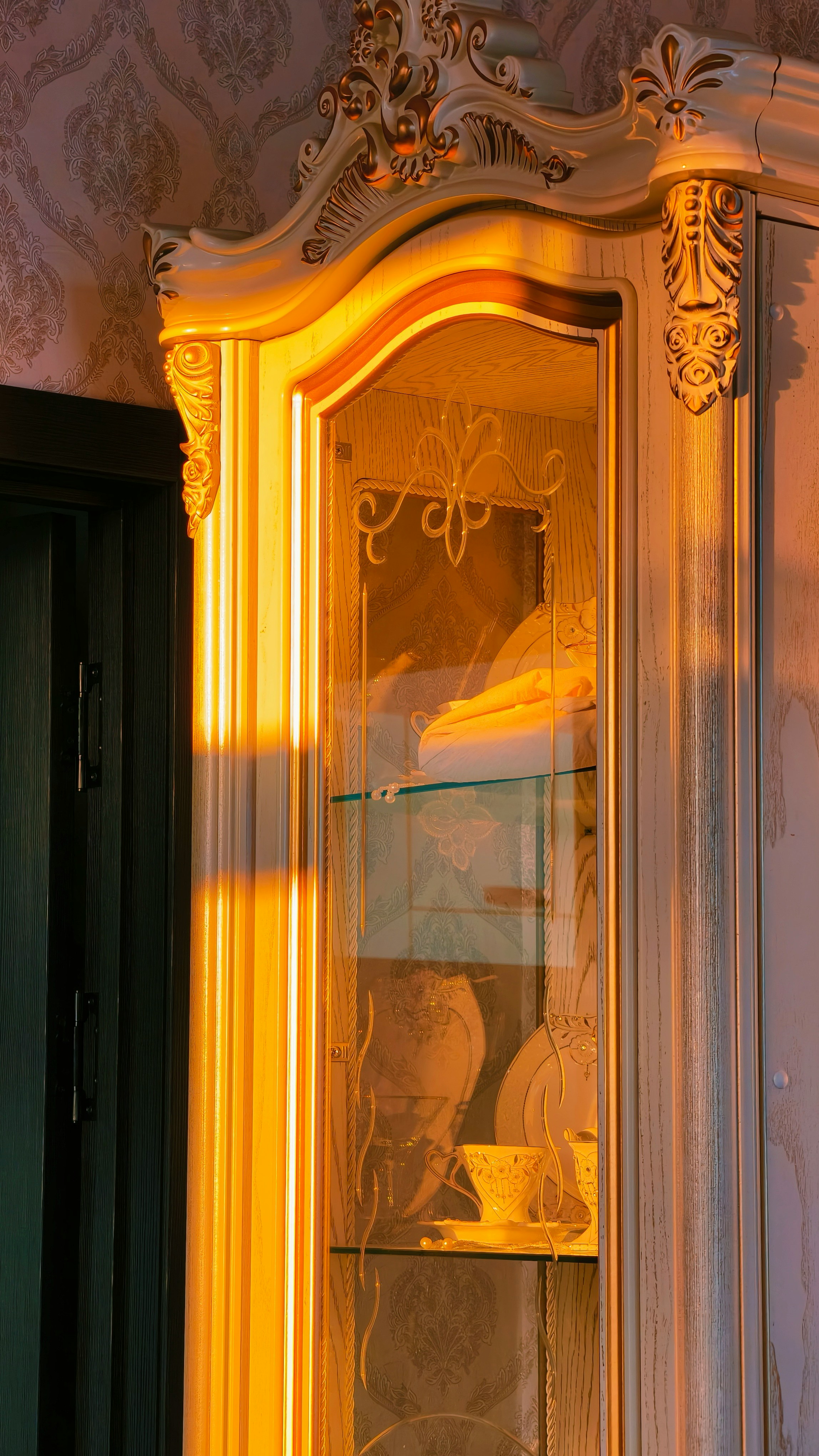 Baroque ornate display cabinet gilded scrollwork carved pediment warm golden light