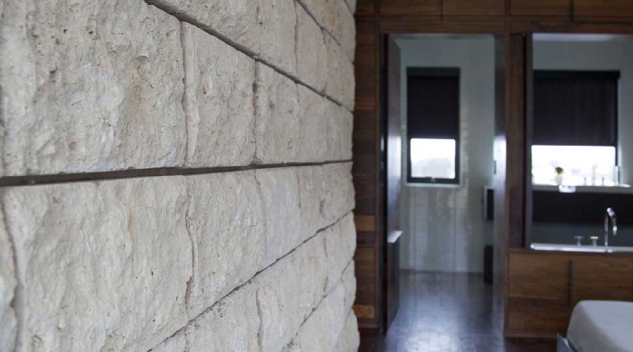Primary bath entry framed by stone block wall and dark wood millwork, Newport Beach