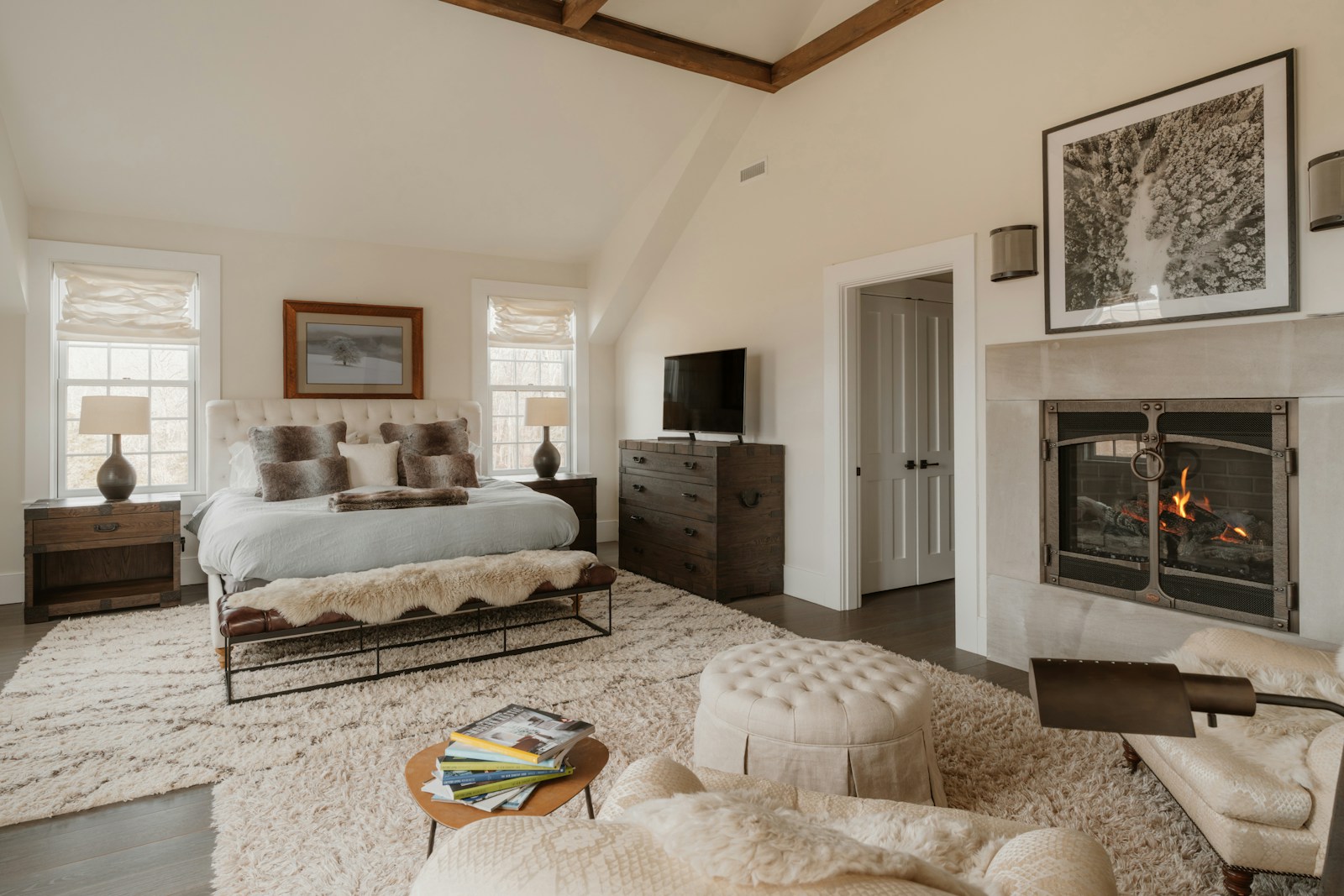 Spacious luxury master bedroom with fireplace, vaulted ceiling, and custom bed