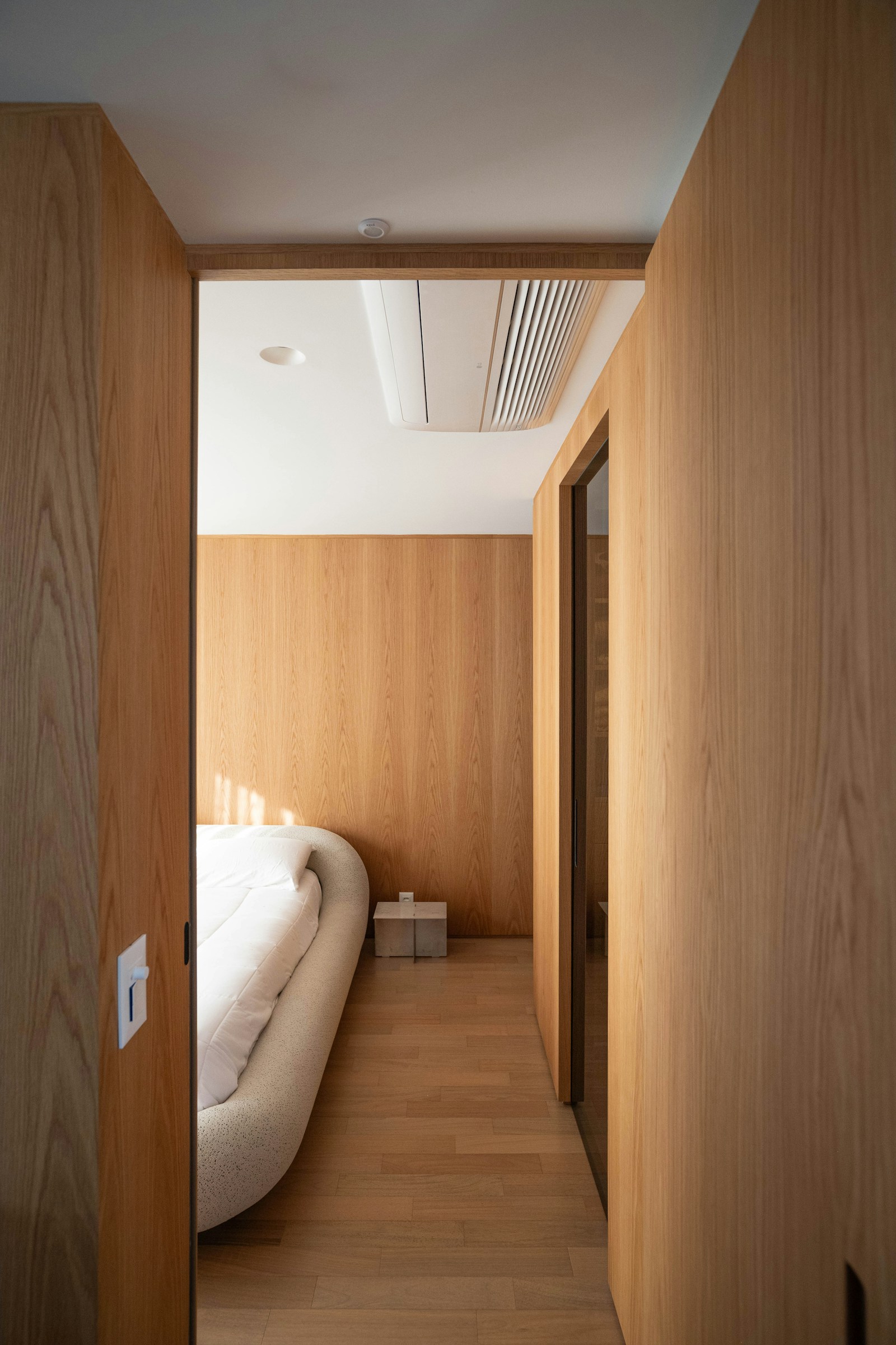 Modern wood-paneled bedroom with custom bed frame and warm natural tones