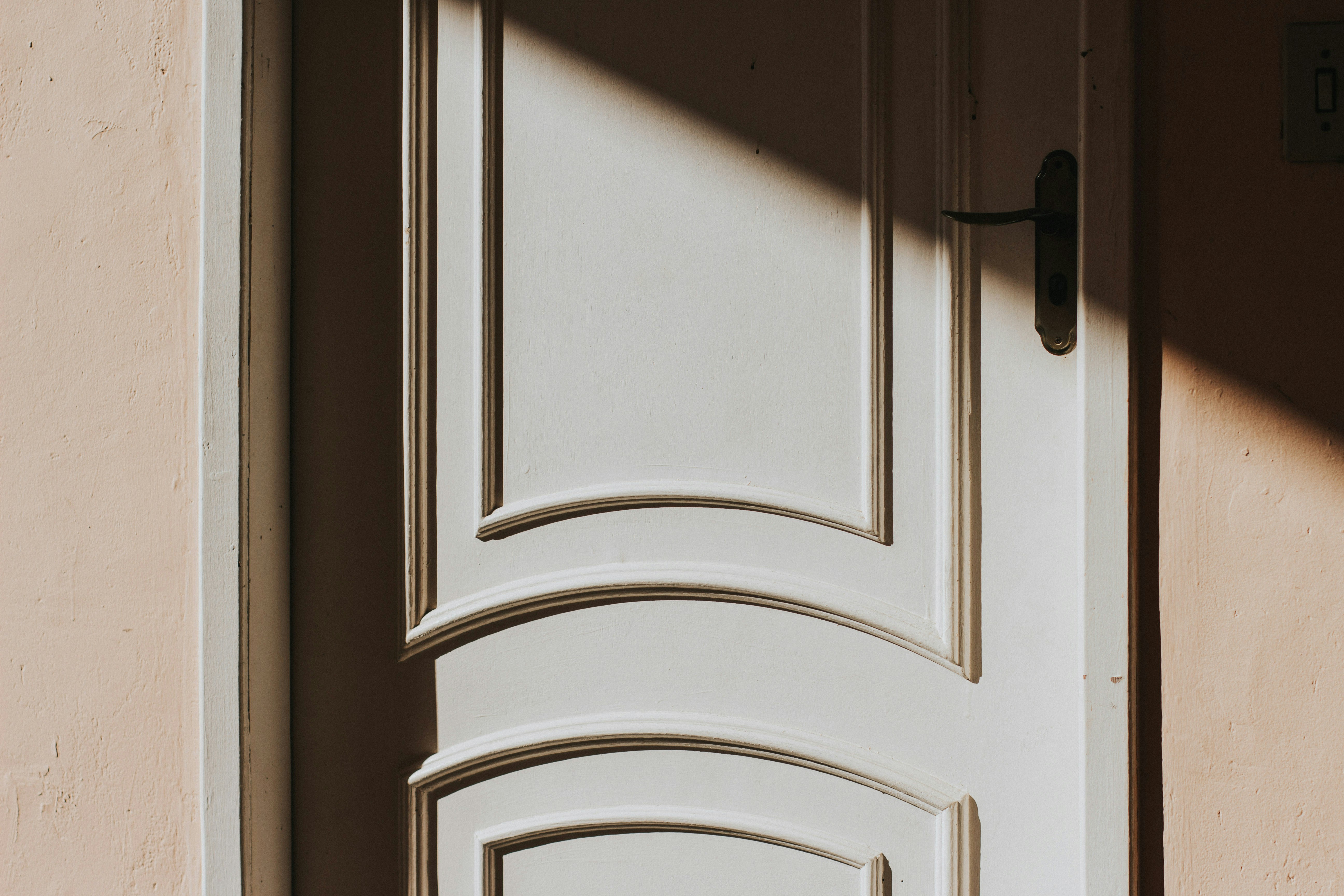 White arched interior door with raised panel molding detail in warm natural light