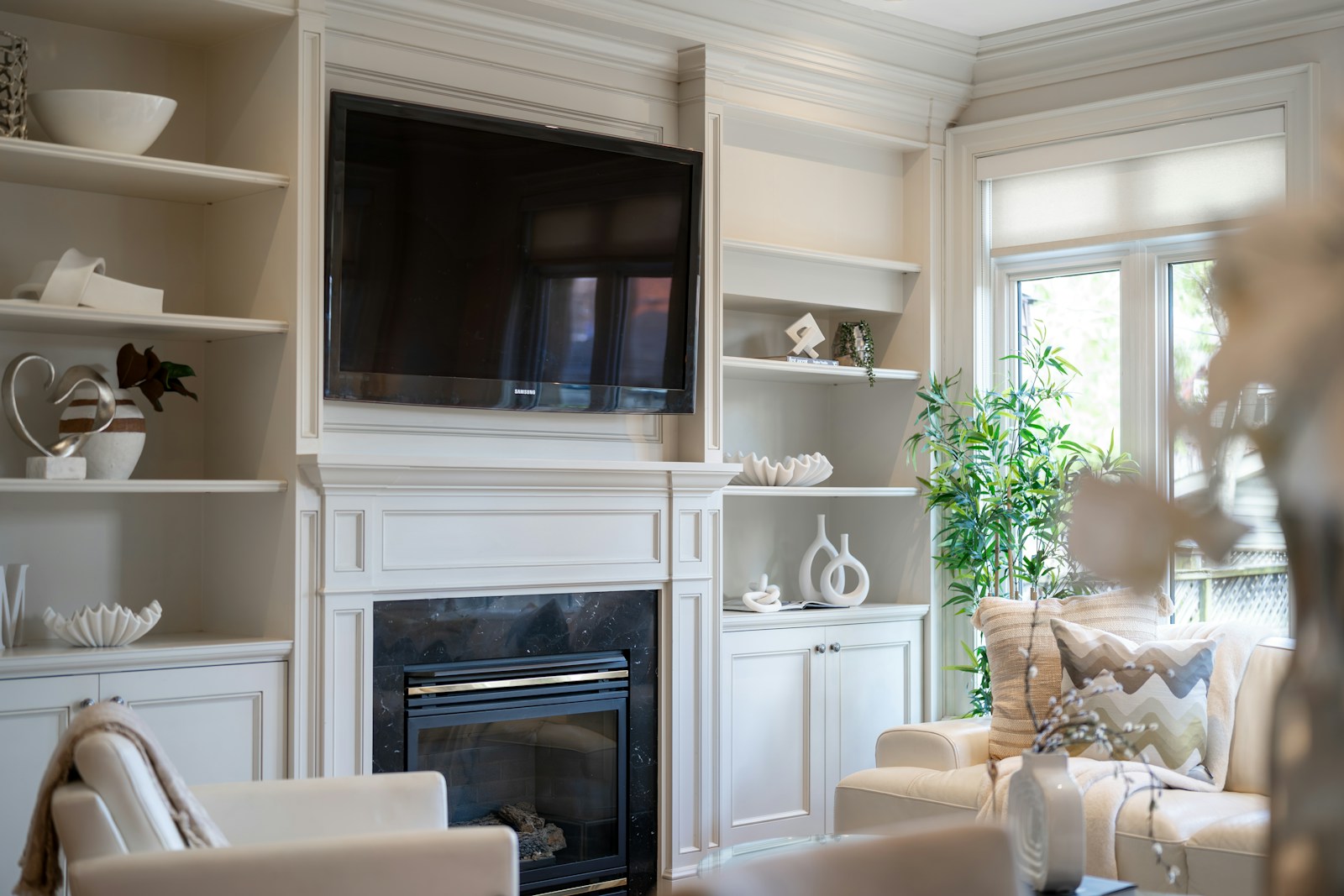Built-in TV cabinetry with white fireplace surround and integrated shelving display