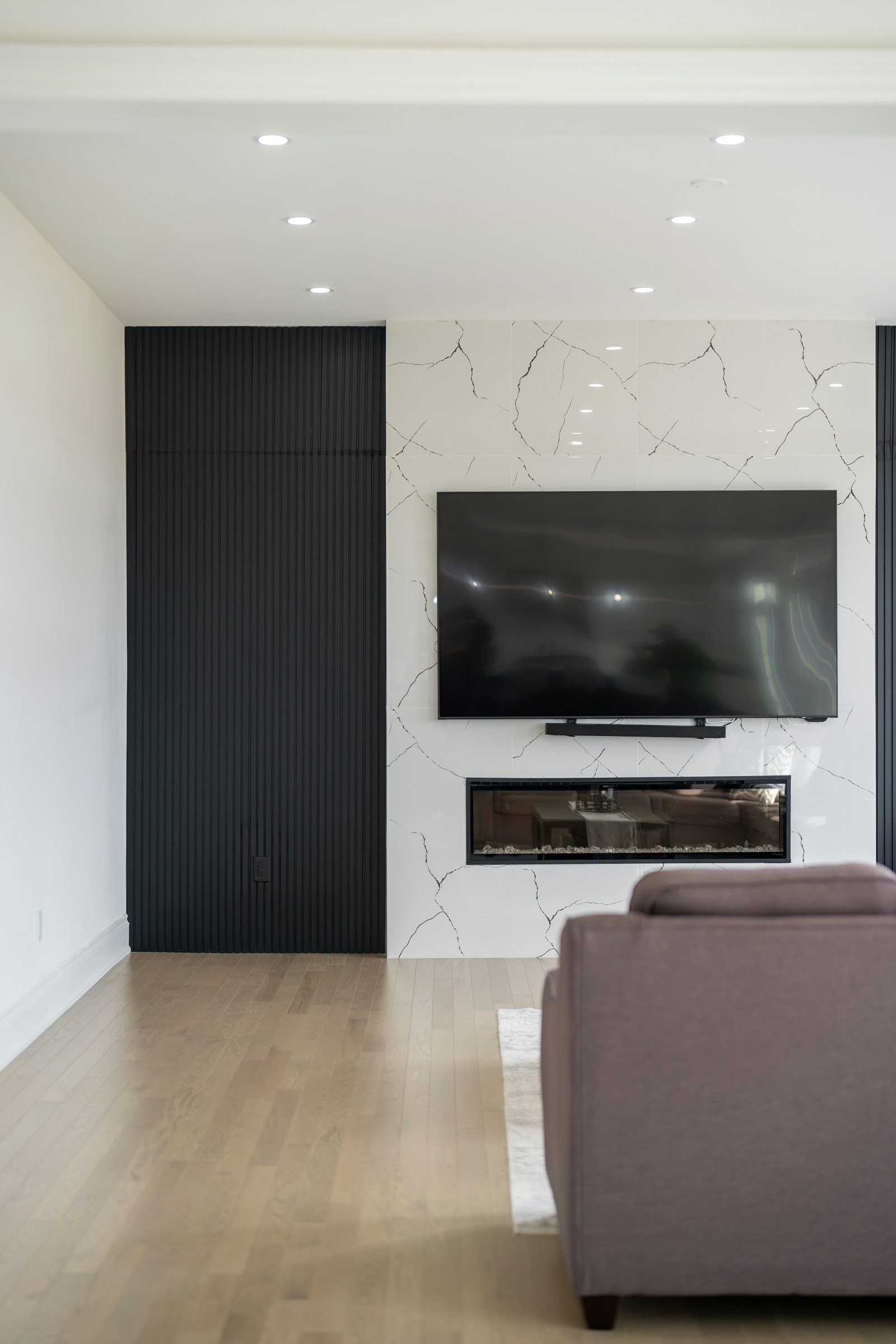 Custom TV media wall with marble surround and built-in fireplace in luxury residence