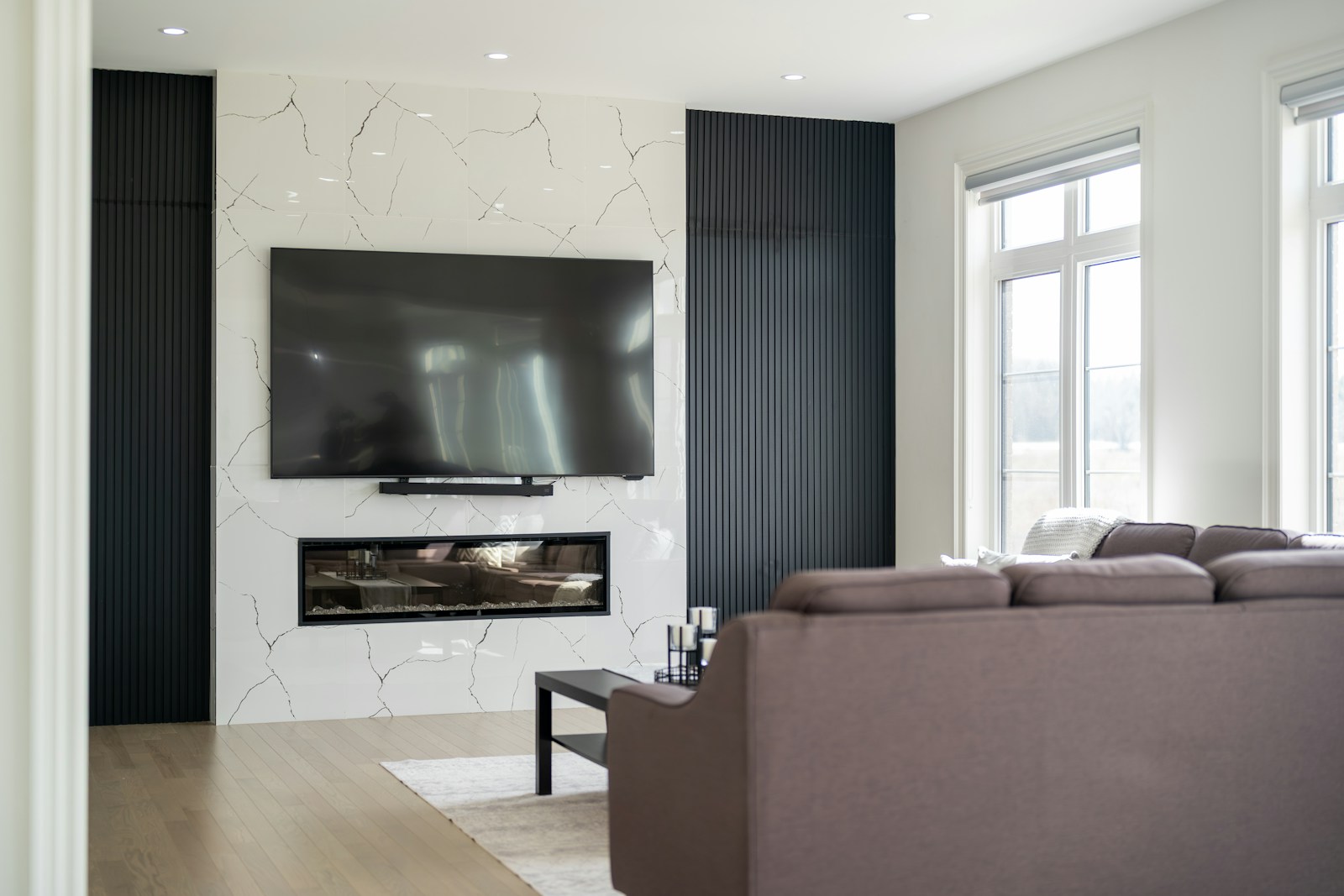 Luxury living room with motorized TV installation above marble fireplace wall