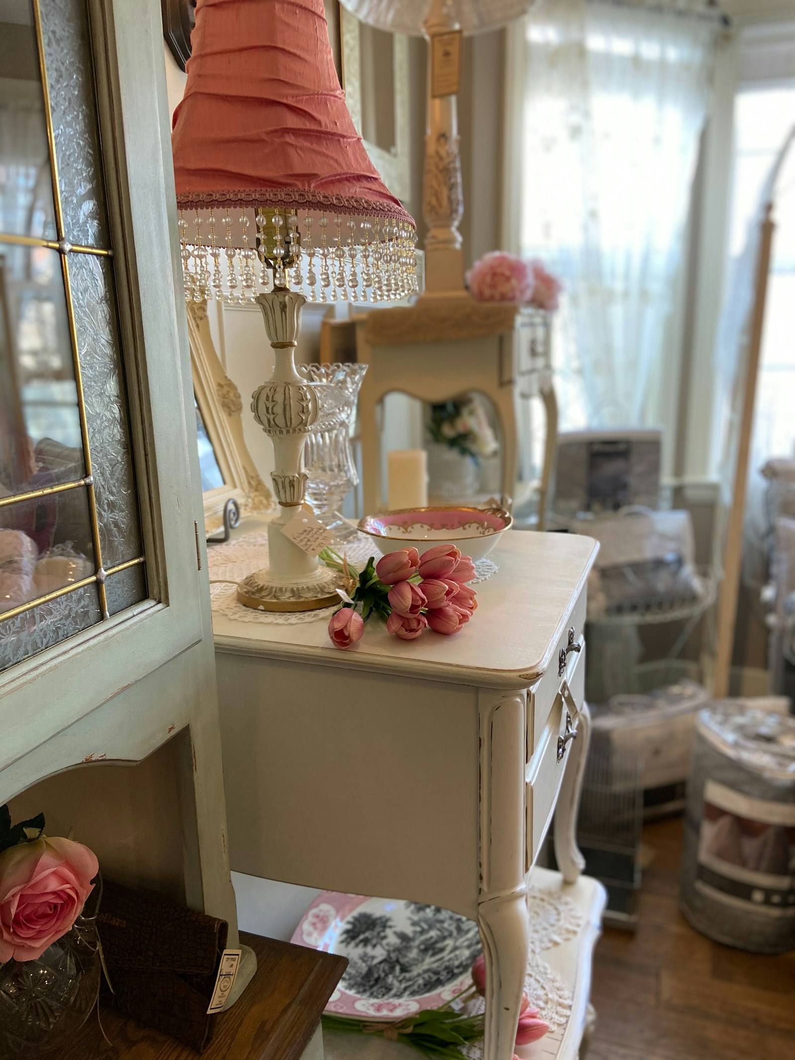 Shabby chic vintage side table with distressed white paint and ornamental lamp