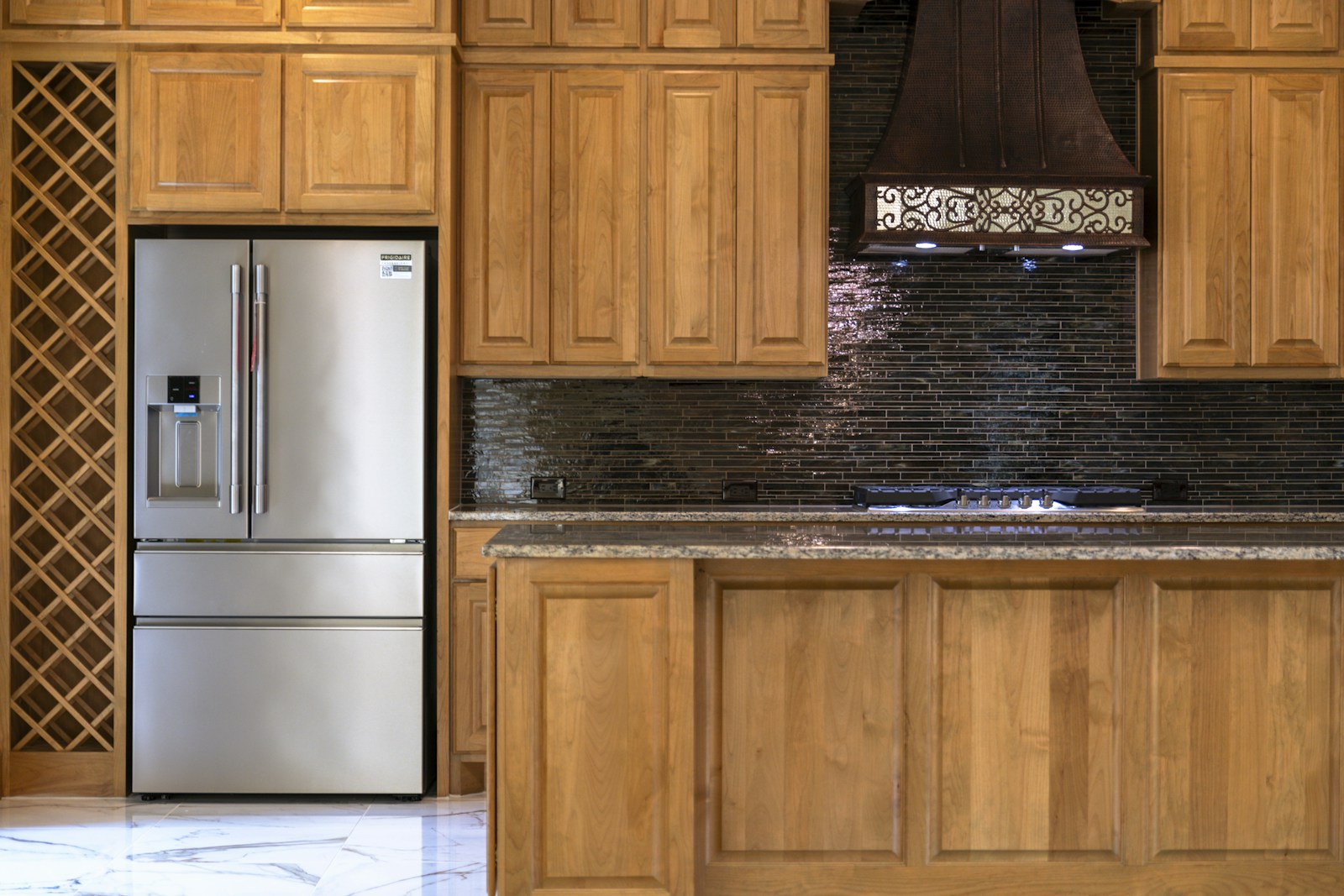 Traditional raised-panel wood kitchen with stainless appliances and wine rack