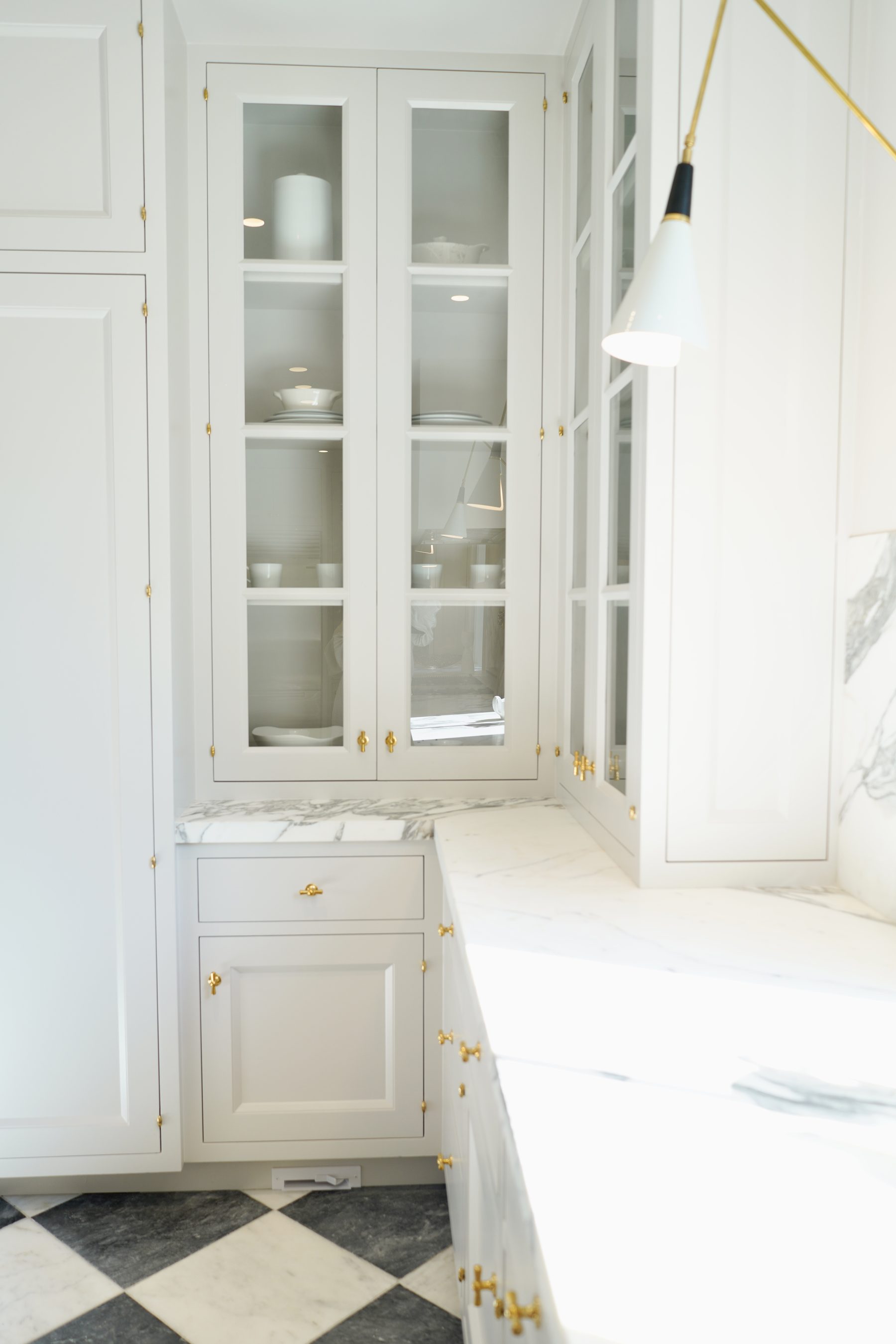 Custom white kitchen glass-front cabinets marble countertop brass