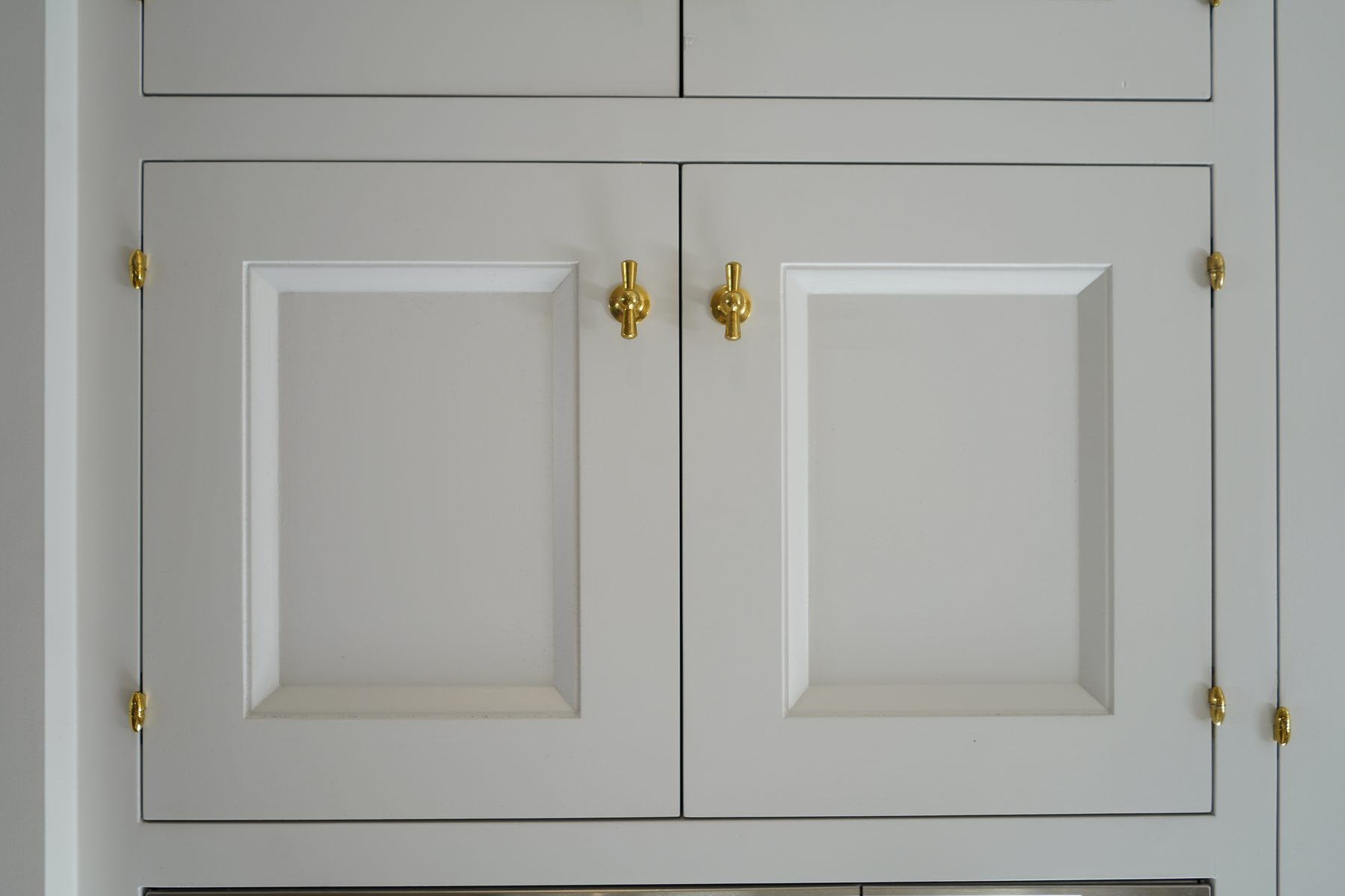 Custom white kitchen cabinet door brass tee knob detail