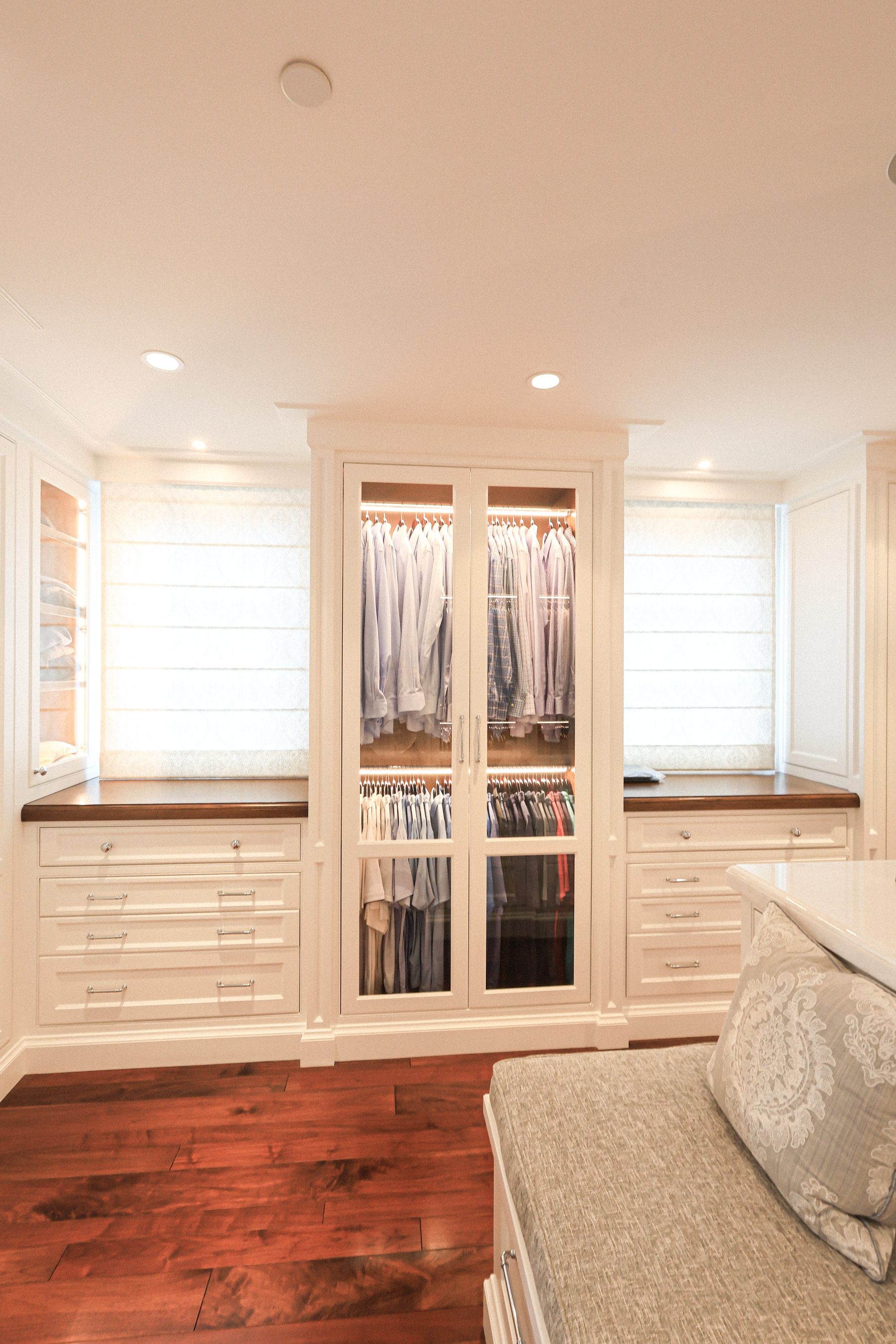 Custom his master closet white glass-front built-in cabinetry