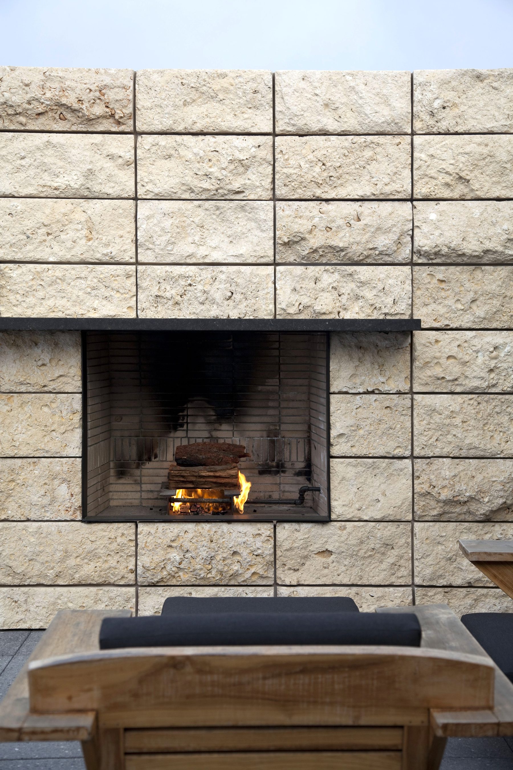 Newport Beach outdoor stone fireplace burning night