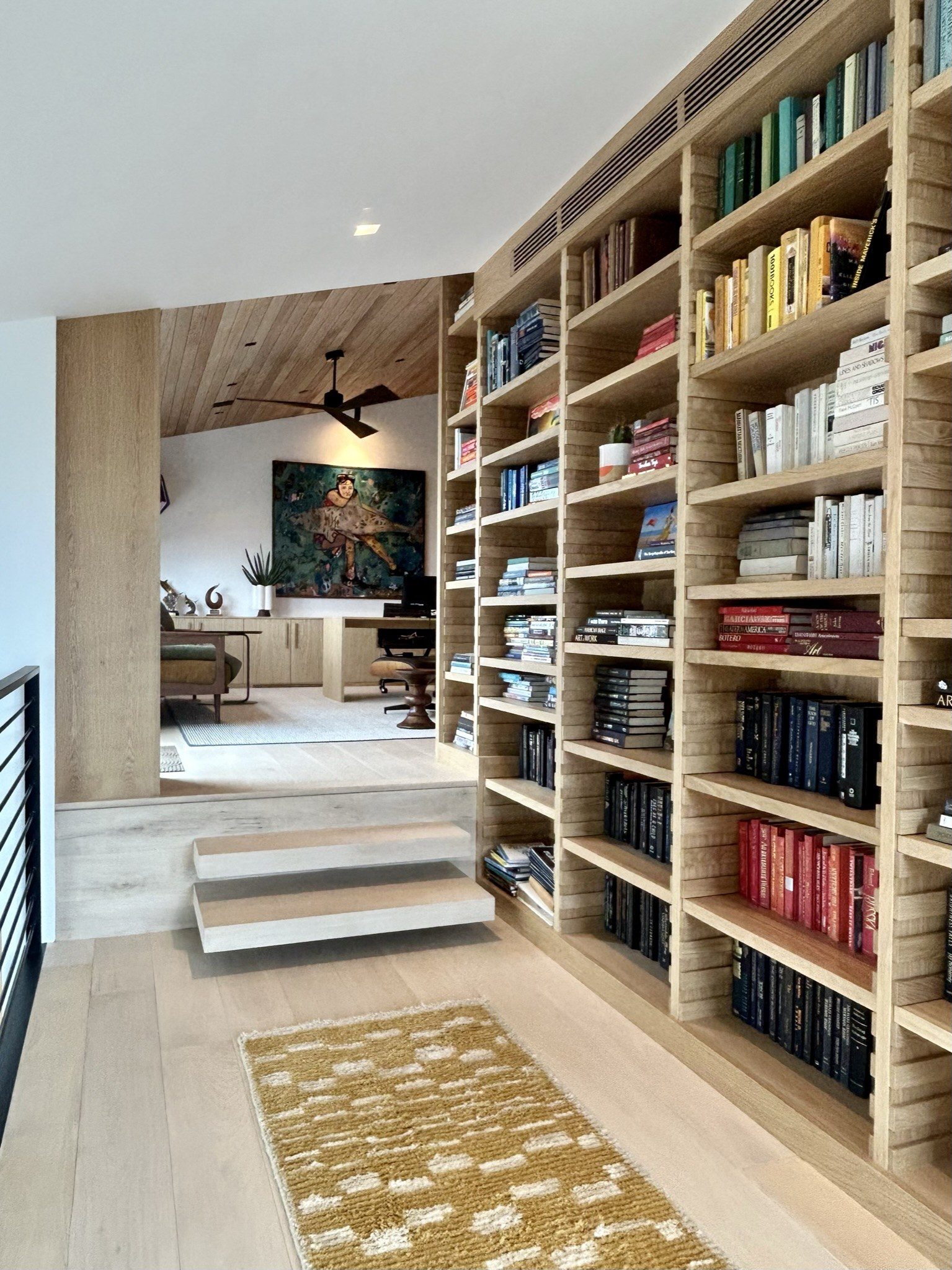 Custom white oak bookcase hallway with room beyond view