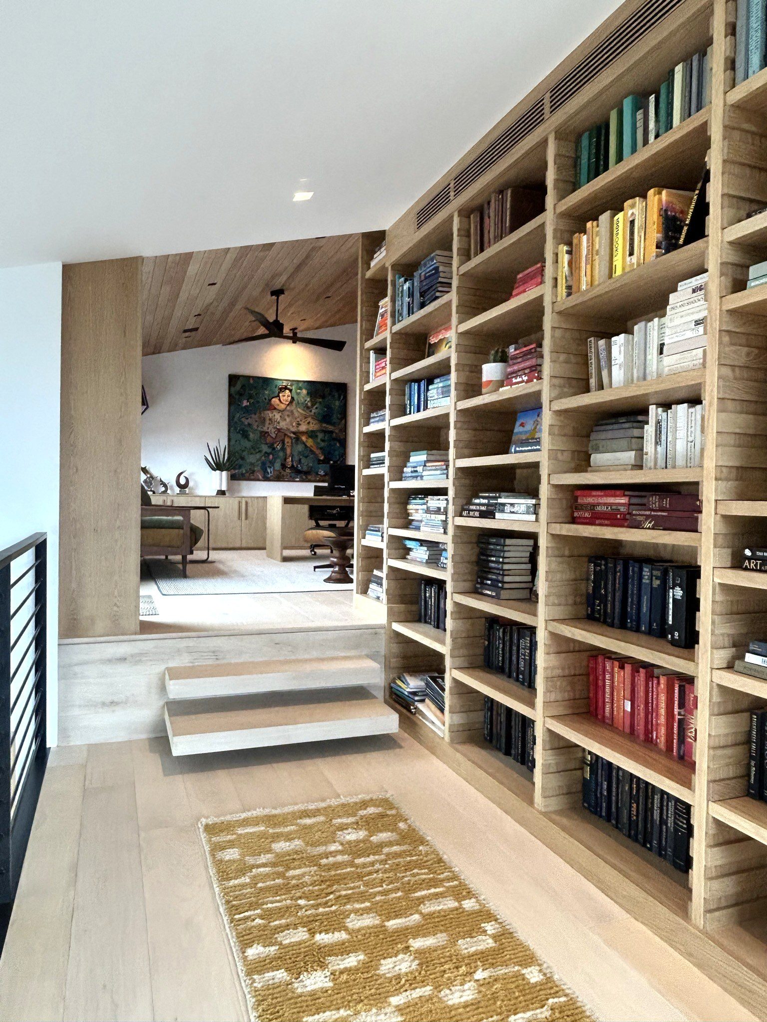 Custom white oak floor-to-ceiling bookcase hallway library
